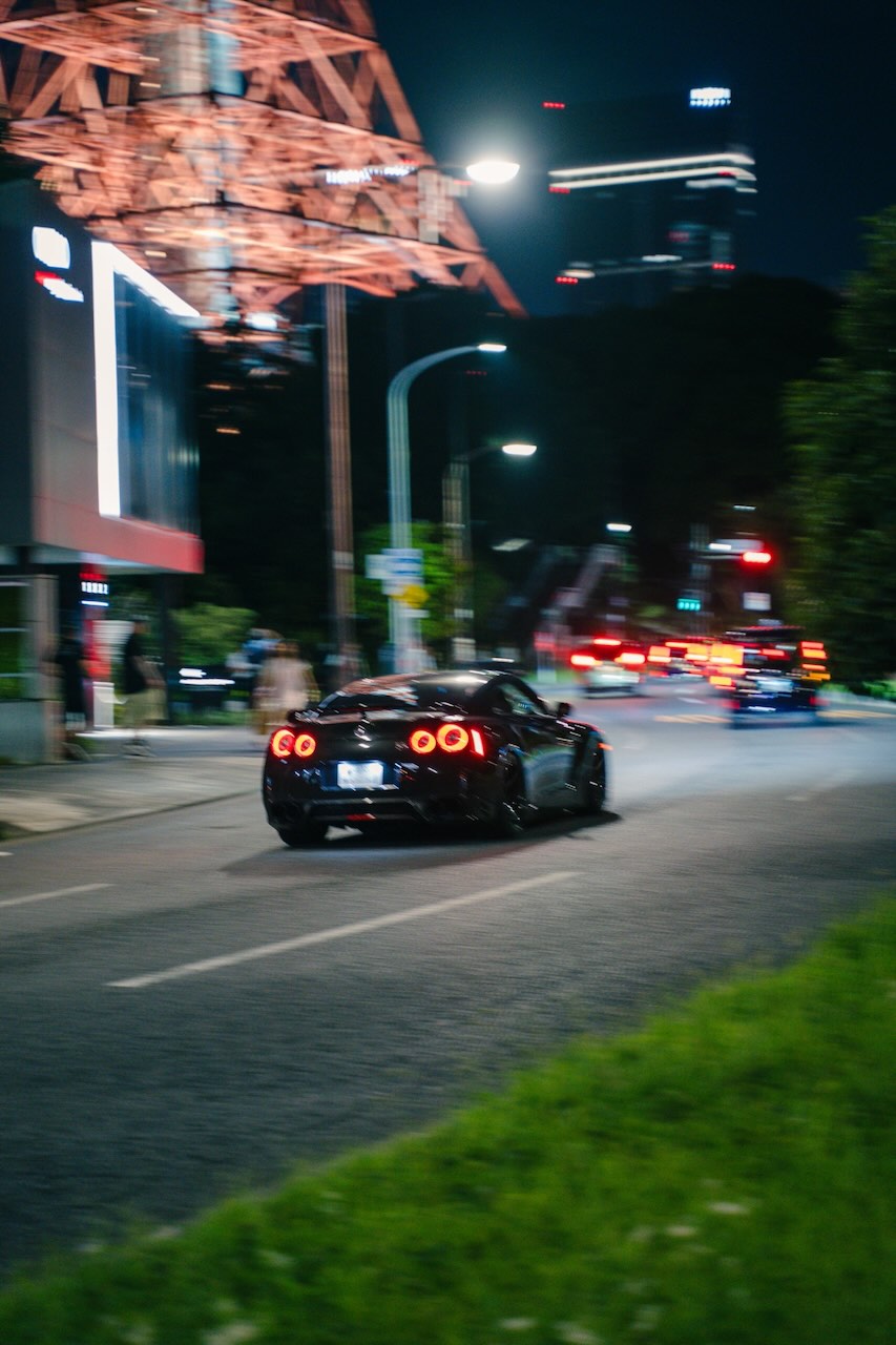 Nissan GT-R R35 driving away beneath Tokyo Tower at night
