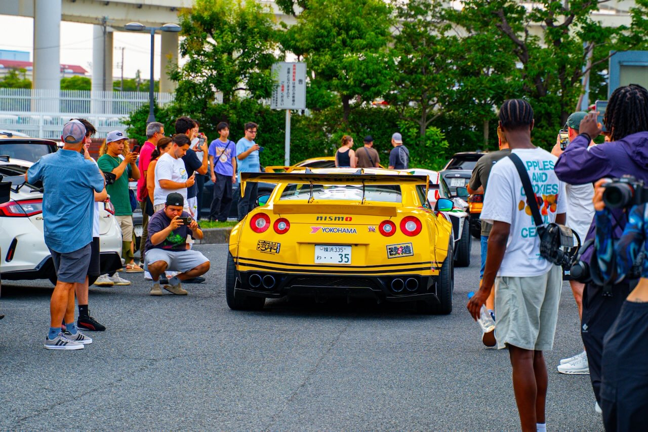 Rear of a yellow Nissan GT-R R35 Nismo surrounded by photographers at Daikoku PA