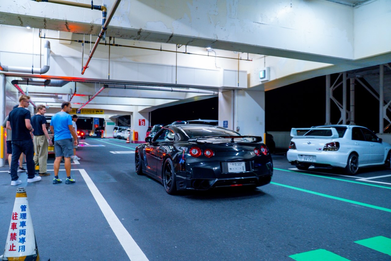 Black Nissan GT-R R35 seen from behind in a Tokyo parking garage at night