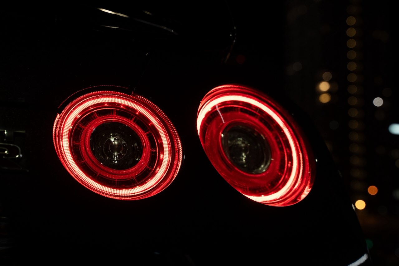 The four round taillights of a Nissan GT-R R35 glowing at night in Tokyo