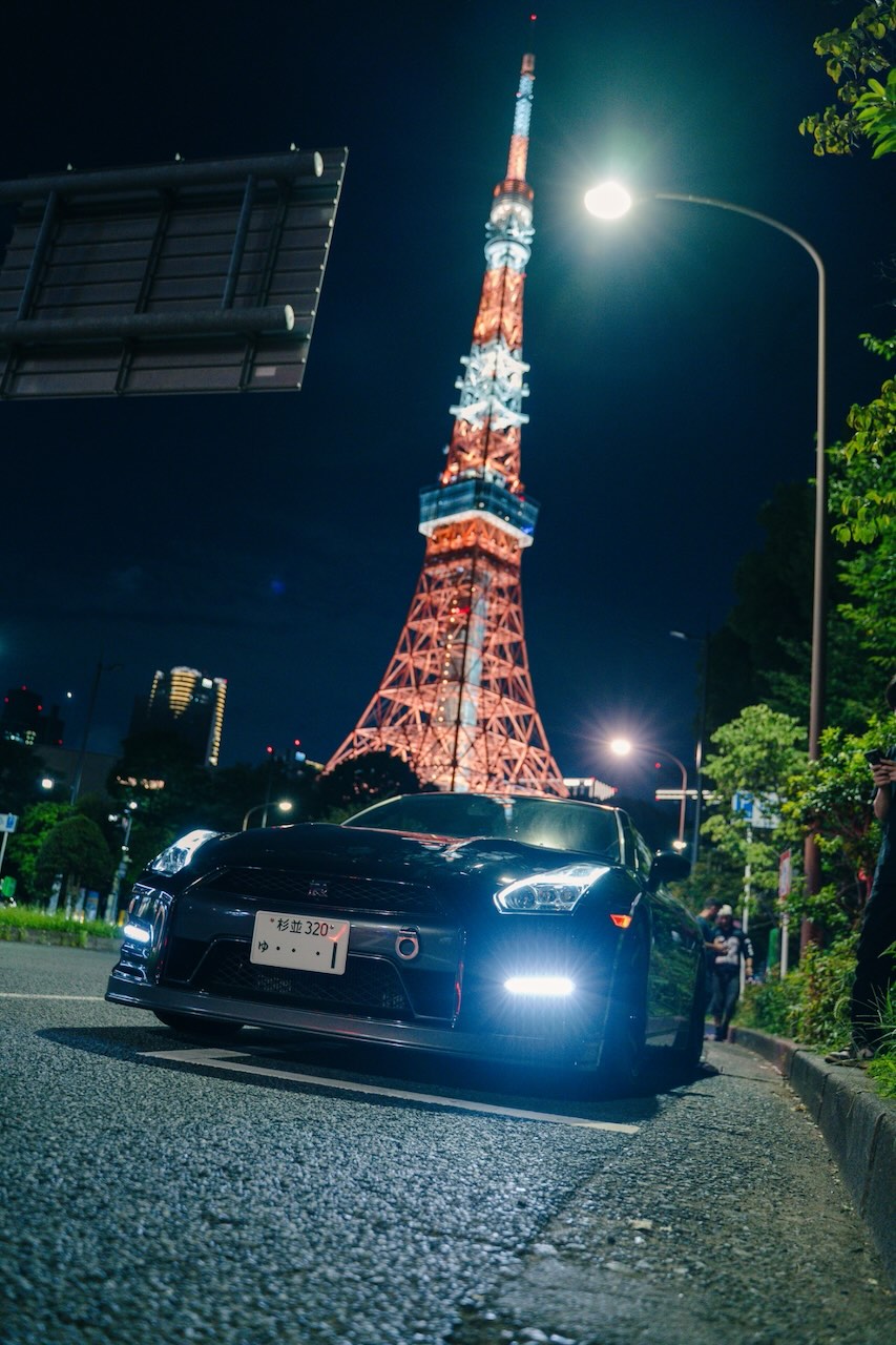 Nissan GT-R R35 parked in front of Tokyo Tower lit up at night