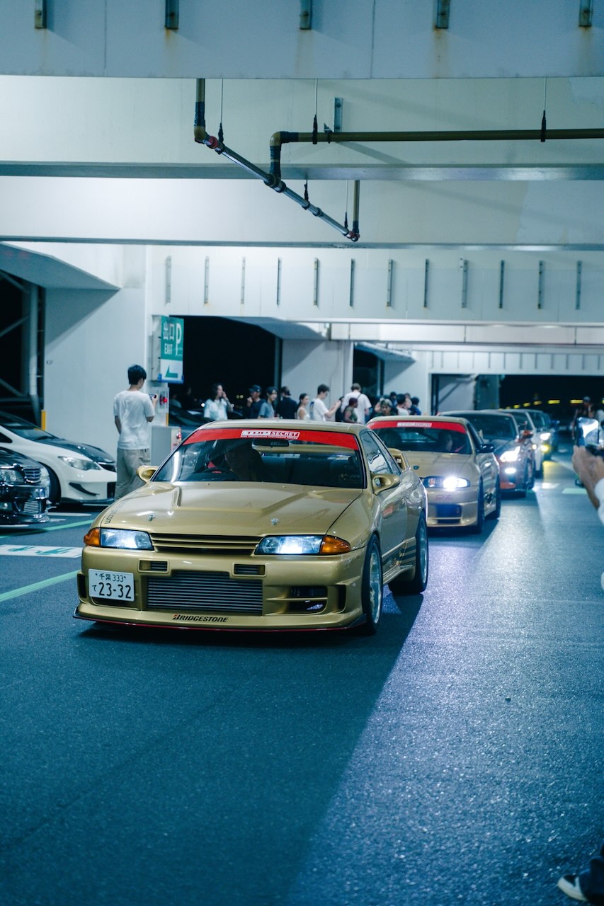 Gold Nissan Skyline GT-R R32 leading a convoy of Skylines at night in Tokyo
